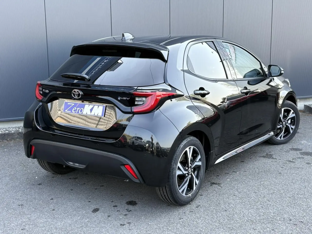 Toyota Yaris Hybride 2025 noir intense vue 3/4 arrière droit avec jantes alliage et vitres surteintées.