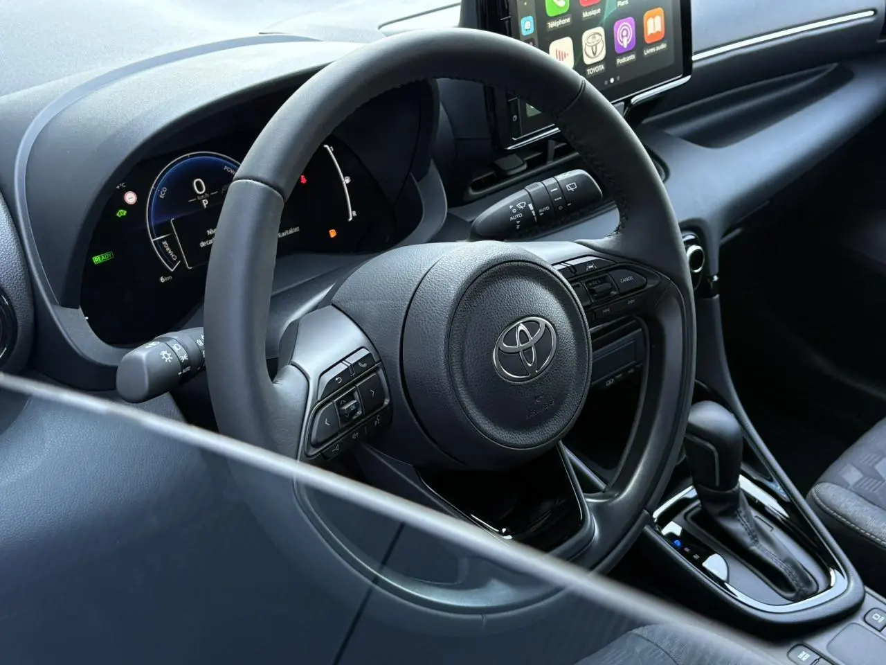 Intérieur de la Toyota Yaris Hybride 2025 vu côté conducteur, volant cuir et tableau de bord numérique noir.