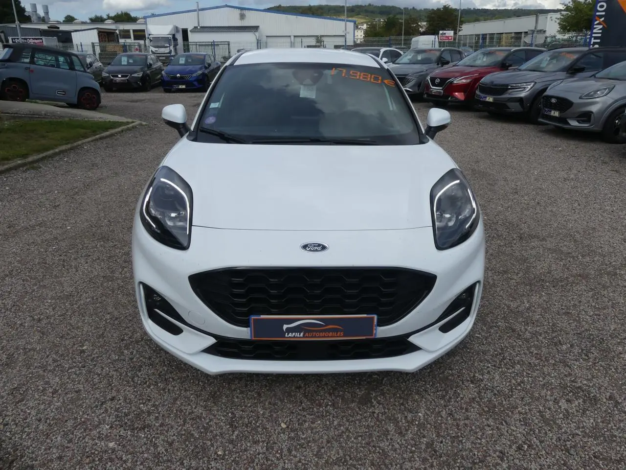 Vue avant d'une Ford Puma blanche ST Line avec calandre noire et phares LED, sur un parking extérieur.