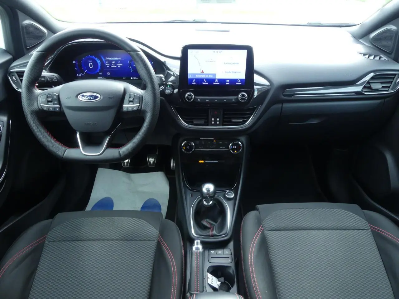 Intérieur noir du Ford Puma 2020 ST Line, vue frontale du tableau de bord avec volant sport et écran tactile central.