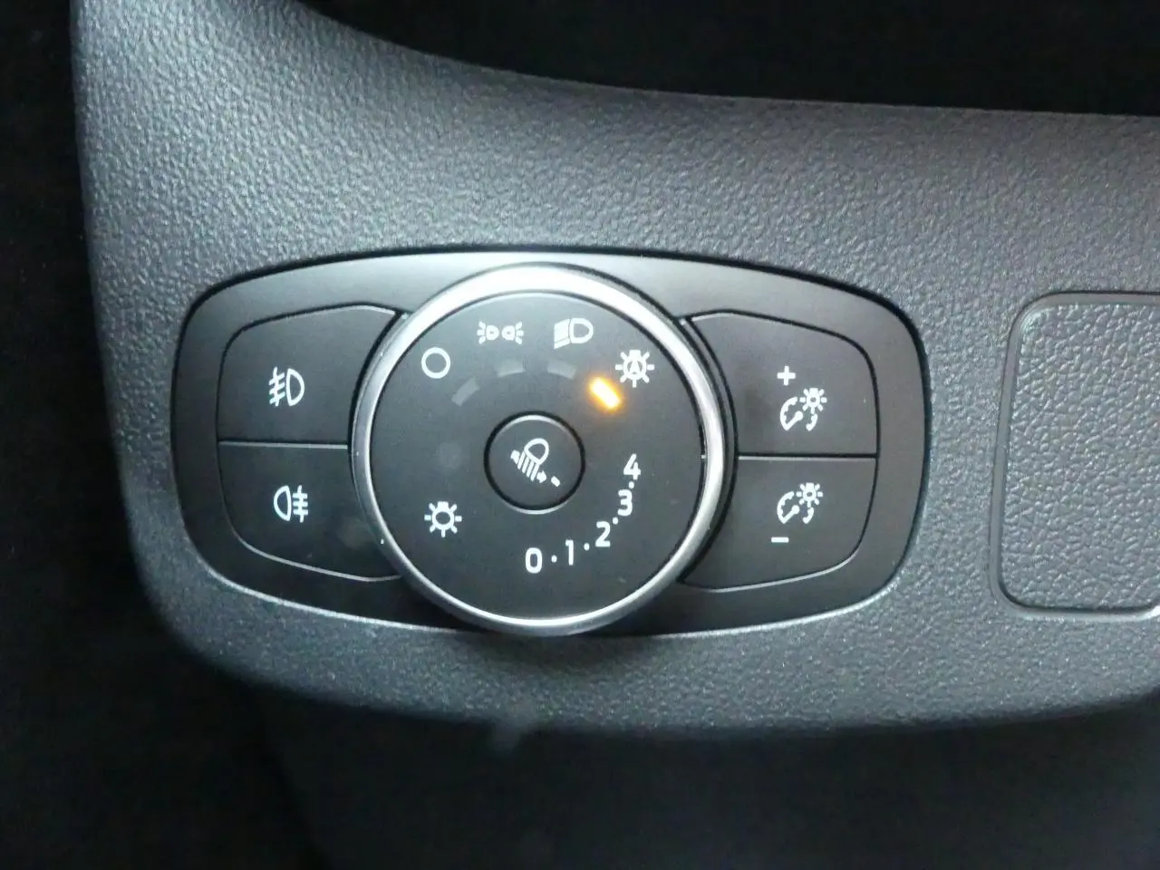 Gros plan sur la commande d'éclairage intérieure du Ford Puma 1.0 EcoBoost blanc, avec bouton rotatif allumé.