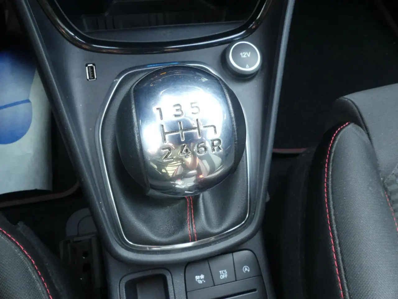 Gros plan sur le levier de vitesses manuel chromé avec surpiqûres rouges du Ford Puma blanc finition ST Line.