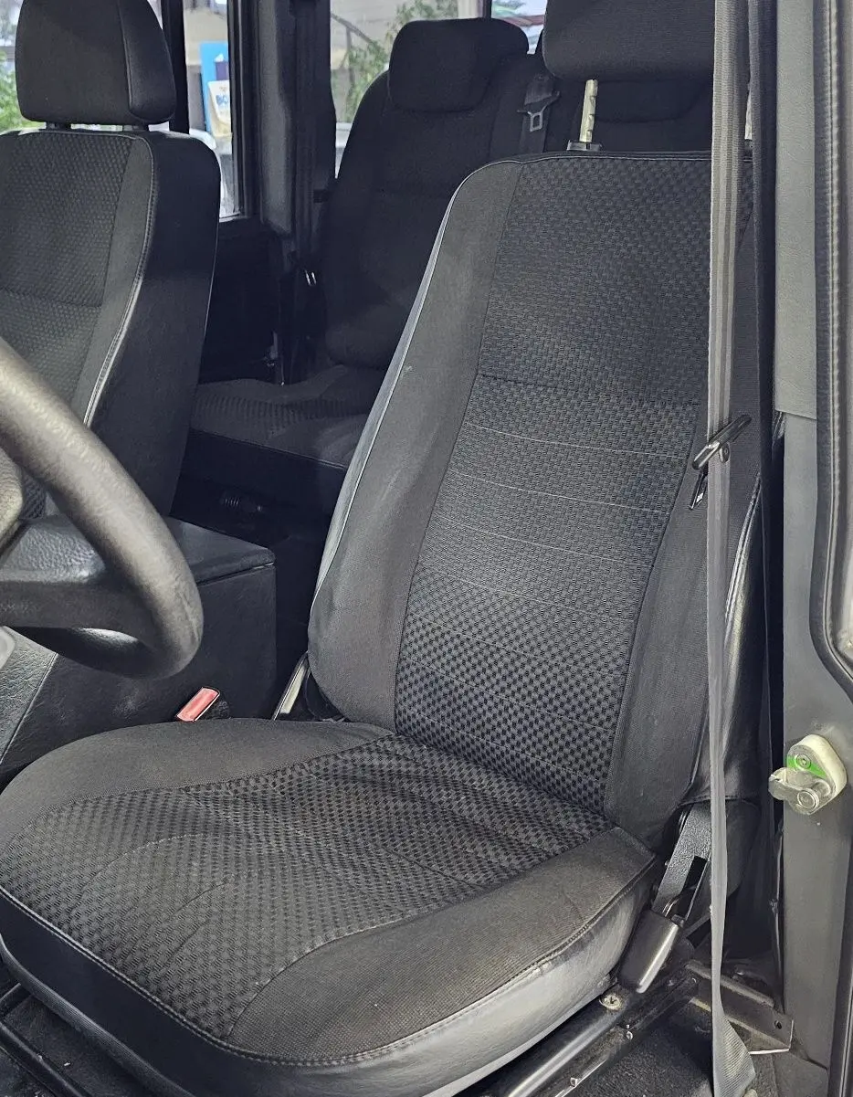 Gros plan sur le siège avant droit noir à motifs du Land Rover Defender 110 II Station Wagon gris de 2010.