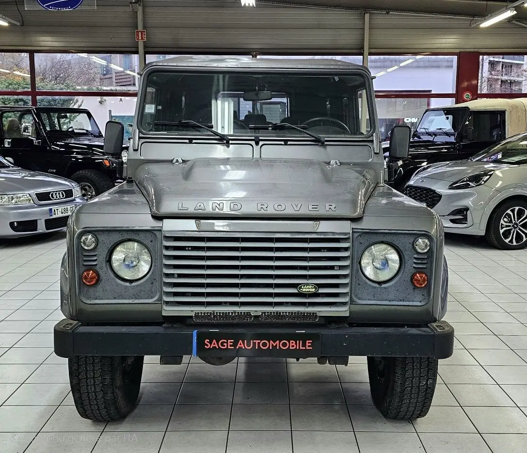 Vue frontale d'un Land Rover Defender 110 Station Wagon S gris 2010, avec calandre distinctive et phares ronds.