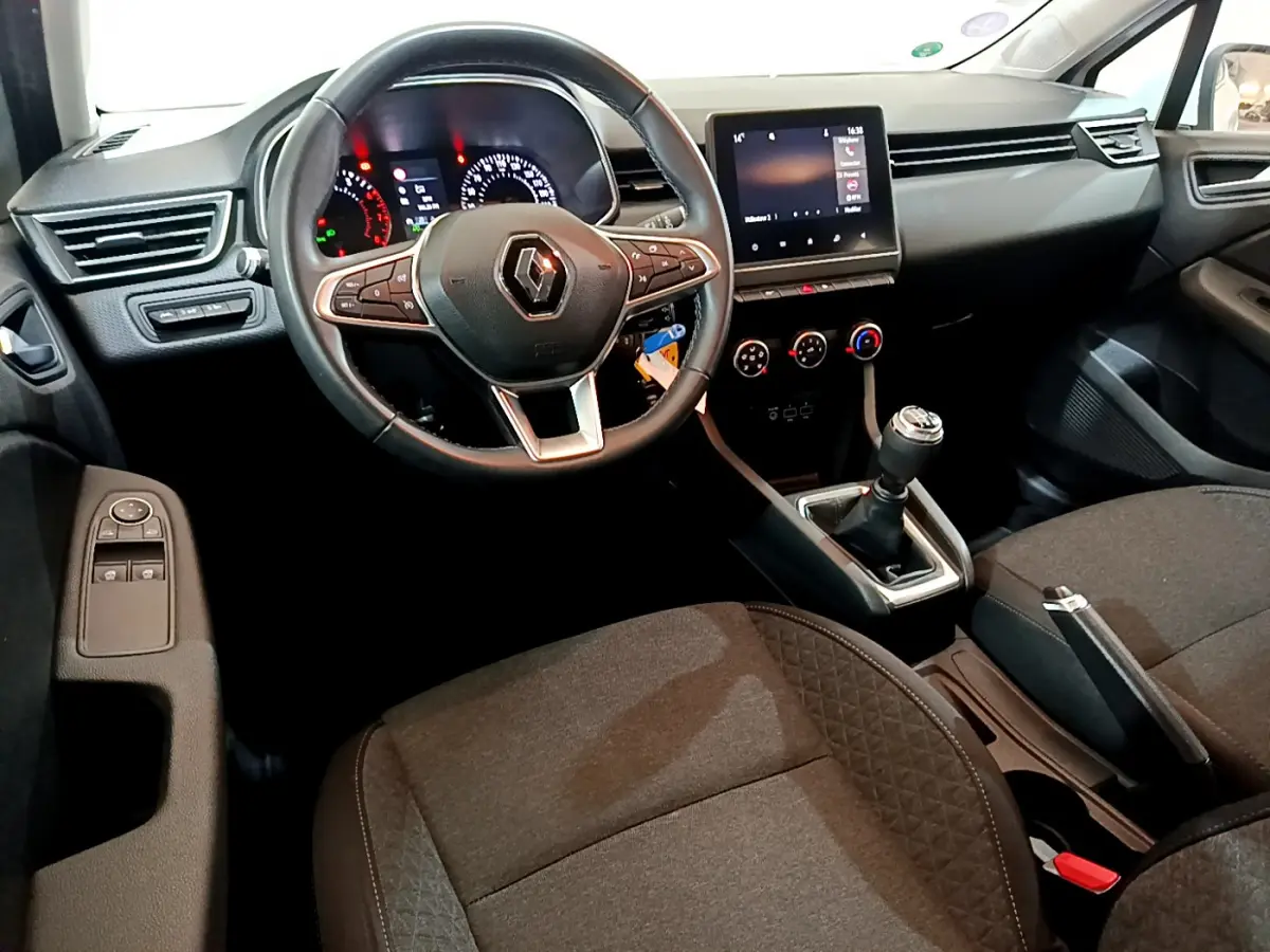 Intérieur de Renault Clio Business 2021 vu côté conducteur, volant cuir, écran tactile et levier de vitesses manuel visibles.