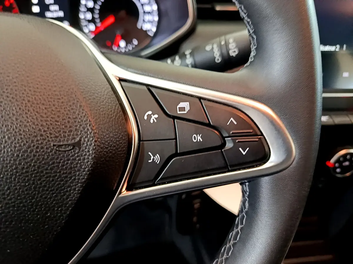 Gros plan sur le côté droit du volant cuir de la Renault Clio Business blanc, avec commandes multifonctions visibles.