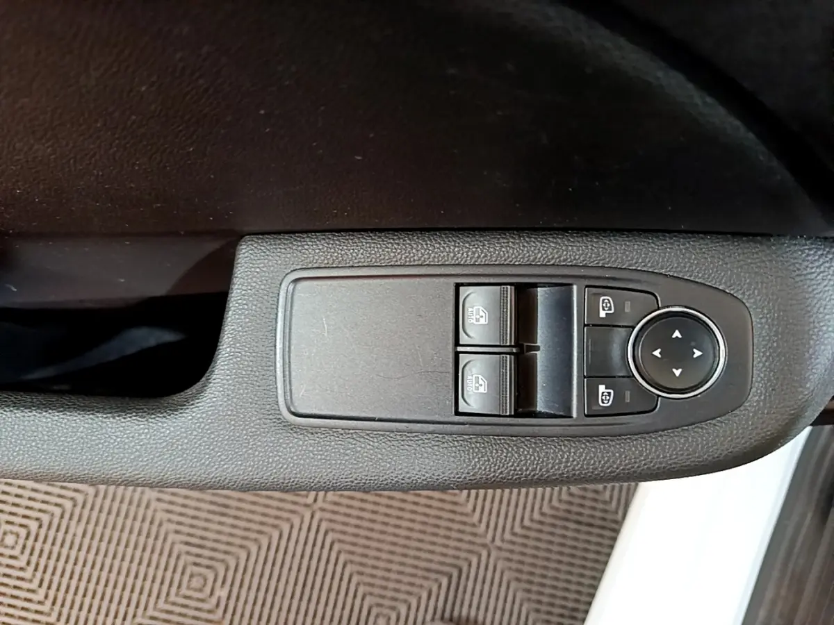 Gros plan sur les commandes de lève-vitres et rétroviseurs côté conducteur d'une Renault Clio Business blanche 2021.