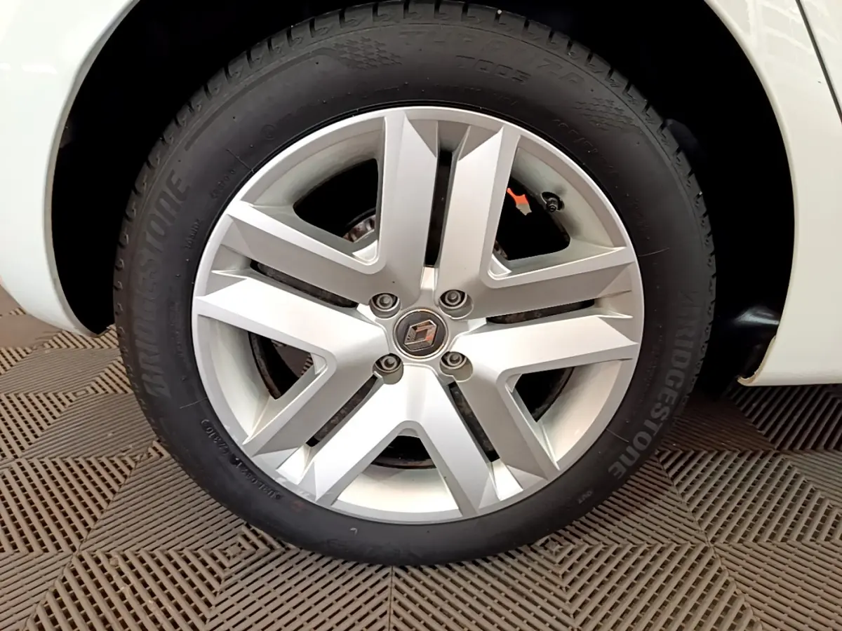 Gros plan sur la roue avant gauche blanche d'une Renault Clio Business 2021 avec jante alliage et logo Renault central.