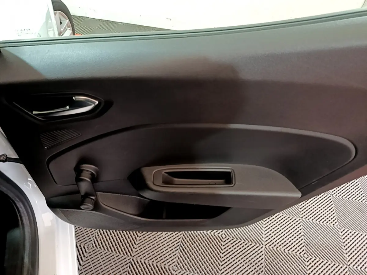 Vue rapprochée de la porte intérieure côté gauche d'une Renault Clio Business blanche, avec poignée et commande de vitre manuelle.