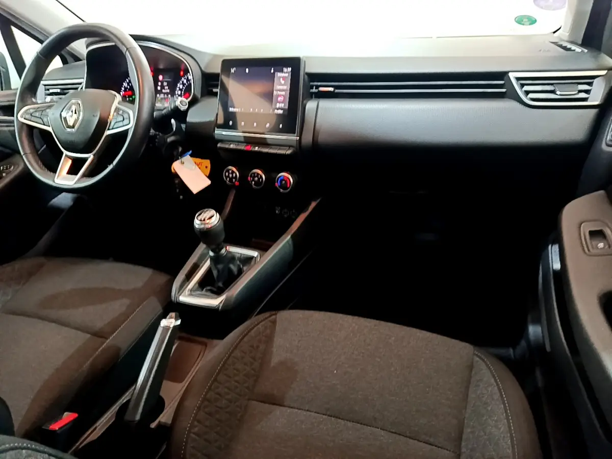Intérieur de Renault Clio Business 2021, vue côté conducteur, volant cuir, écran tactile central et boîte manuelle visible.