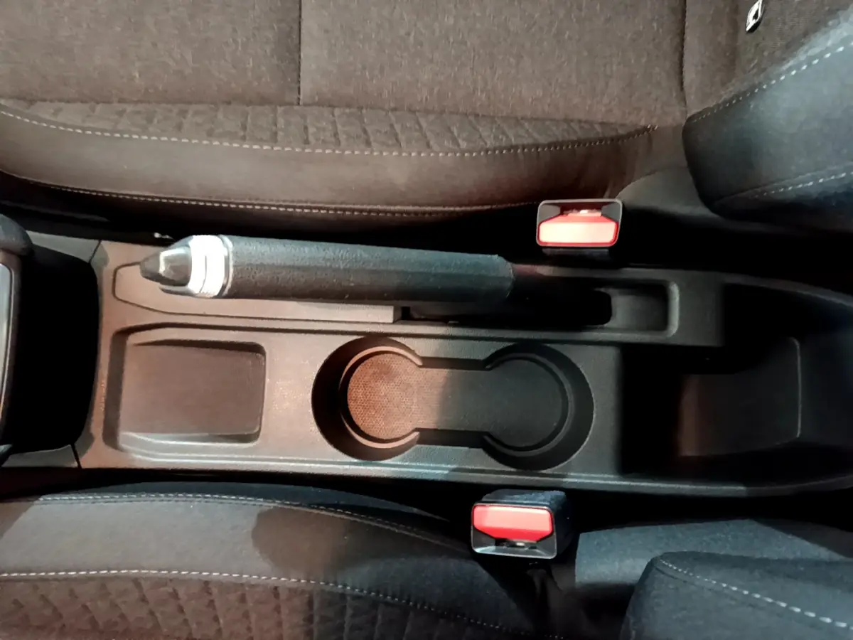 Vue plongeante sur la console centrale noire avec frein à main et porte-gobelets de la Renault Clio Business blanche 2021