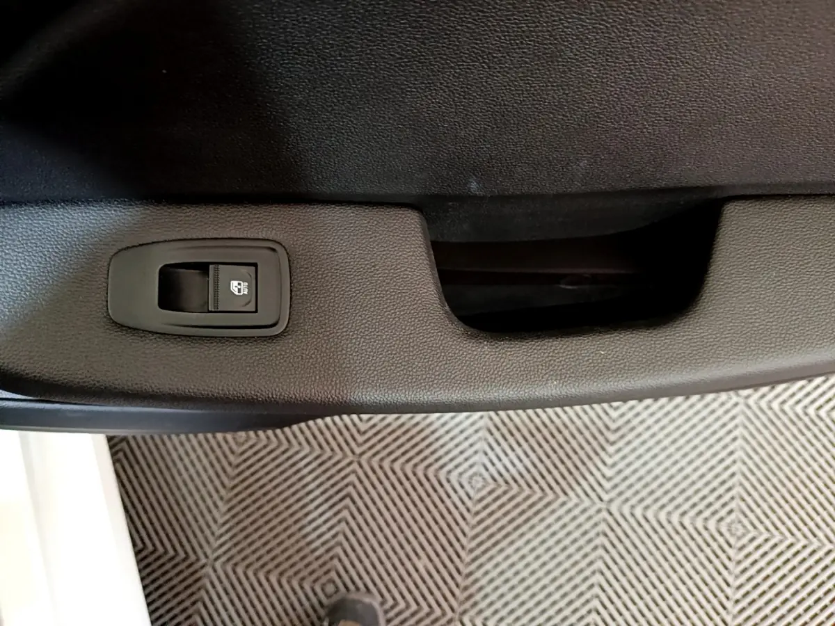 Détail de la commande de verrouillage centralisé sur la porte intérieure côté gauche d'une Renault Clio Business blanche.