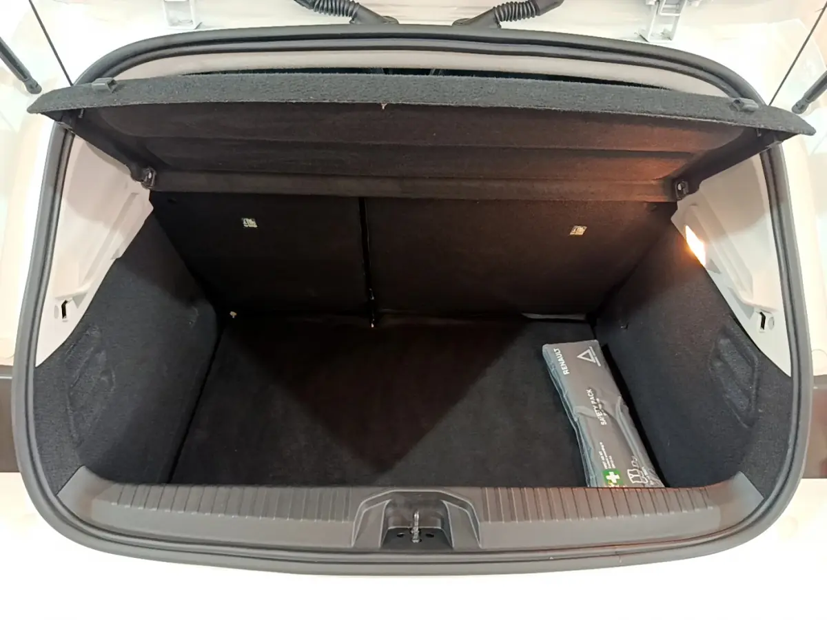 Coffre ouvert vu de l'arrière d'une Renault Clio Business blanche avec trousse de secours visible à droite.