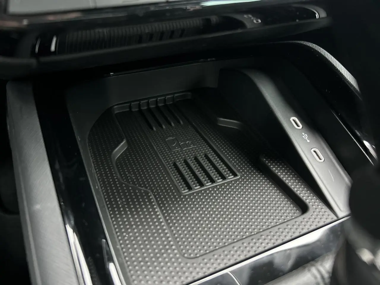 Gros plan sur le compartiment de charge à induction avec deux ports USB-C dans l’habitacle noir du Skoda Kamiq 2025.