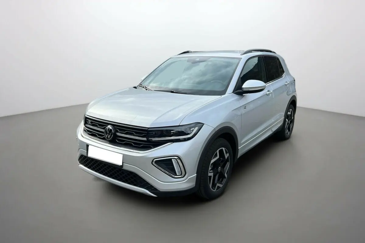 Volkswagen T-Cross gris argent en vue 3/4 avant droit, avec jantes alu 18 pouces et barres de toit noires.