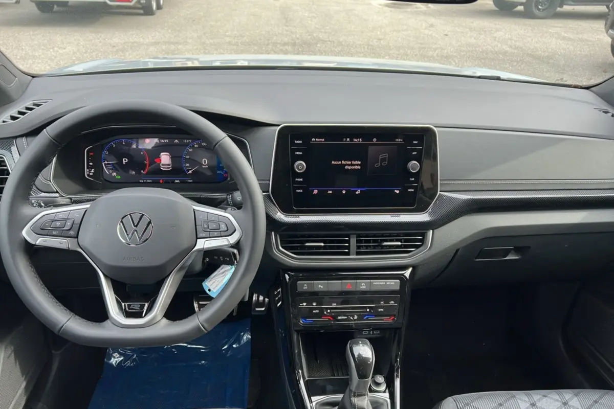 Vue intérieure avant du Volkswagen T-Cross TSI 116 DSG7 R-Line 2025, volant cuir multifonctions et écran tactile central.