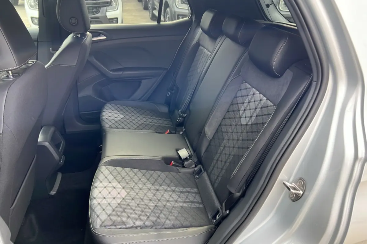 Vue intérieure côté arrière droit du Volkswagen T-Cross gris argent, mettant en valeur la banquette arrière en tissu à motifs géométriques.