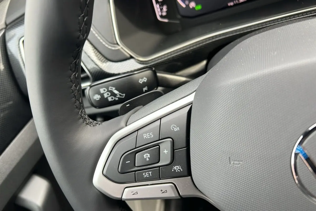 Gros plan sur le volant cuir multifonctions gris du Volkswagen T-Cross TSI 116 DSG7 R-Line 2025, avec commandes intégrées.