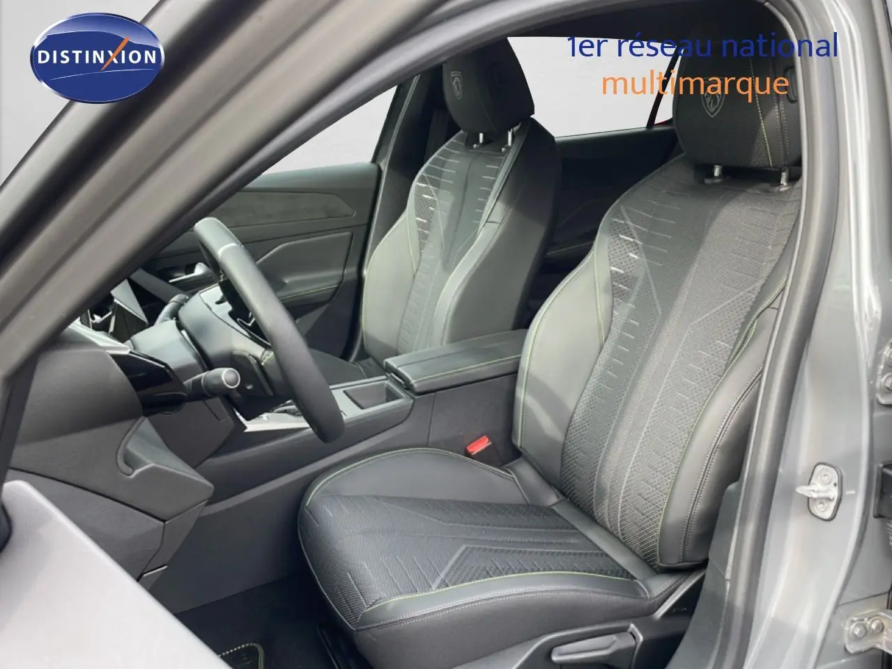Vue intérieure côté conducteur de la Peugeot 308 gris selenium metal, sièges en tissu et cuir avec surpiqûres vertes.