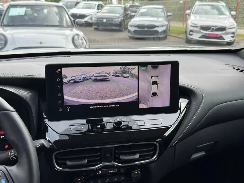 Vue intérieure centrée sur l'écran tactile affichant la caméra de recul et vue 360° du Nissan Juke noir Kuro métallisé.