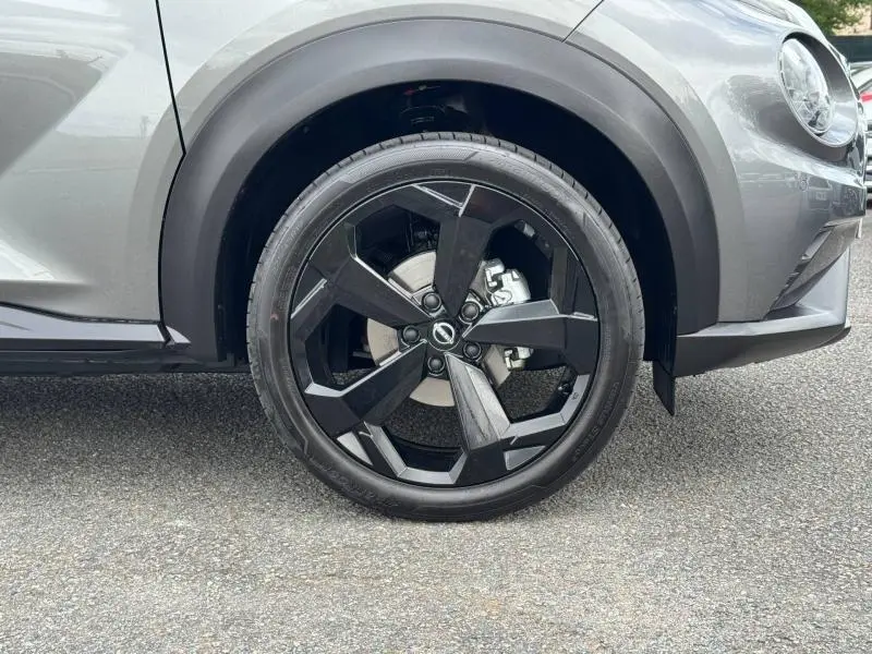 Gros plan sur la roue avant droite du Nissan Juke 2025 noir Kuro métallisé avec jante alu noire au design moderne.