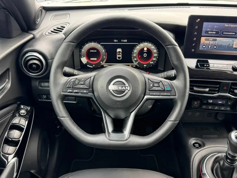 Vue intérieure centrée sur le volant cuir multifonction du Nissan Juke 2025 avec tableau de bord numérique et écran tactile.
