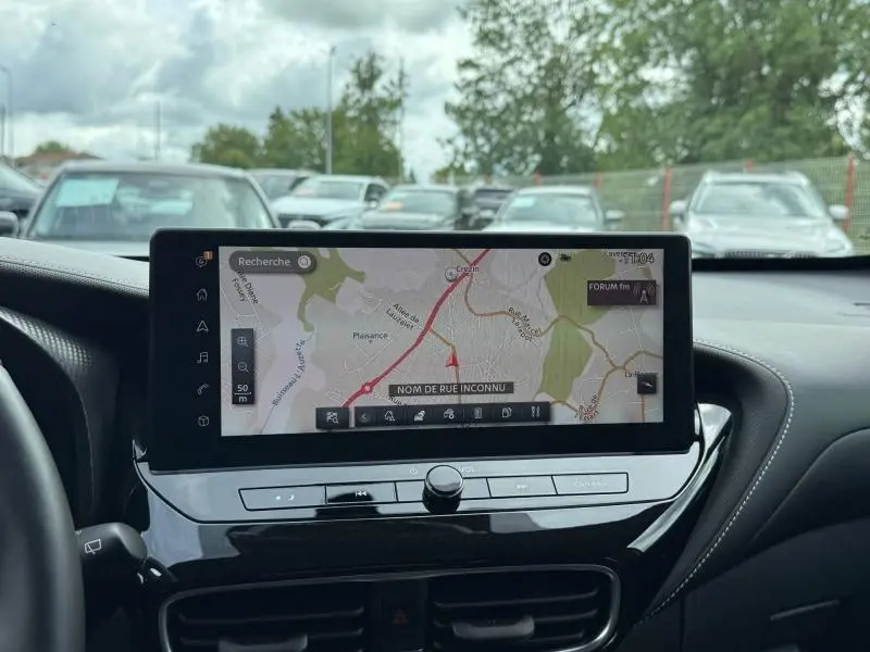 Vue intérieure centrée sur l'écran tactile du tableau de bord du Nissan Juke 2025, ambiance noire élégante.