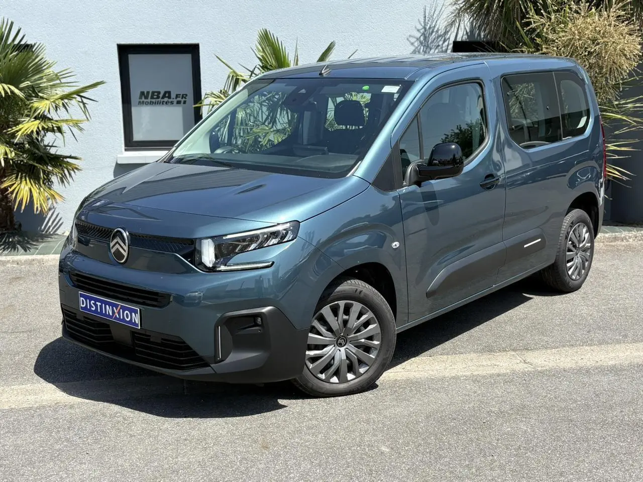 Vue 3/4 avant droit du Citroën Berlingo ë-136 bleu Kiama avec jantes tôles et porte coulissante droite visible.