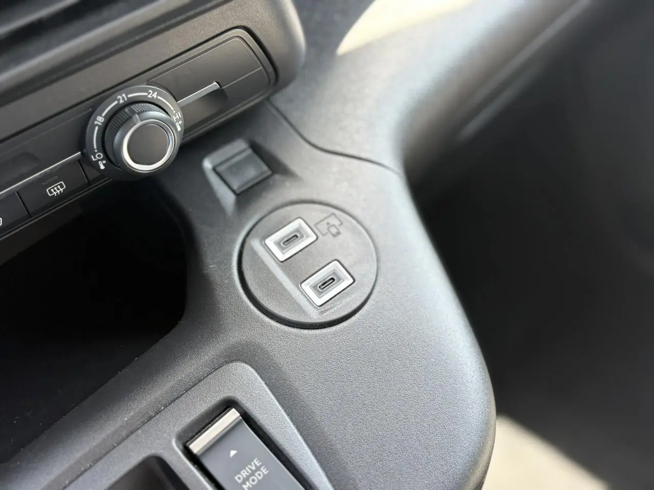 Gros plan sur la console centrale du Citroën Berlingo ë-136 avec deux ports USB-C et un bouton de réglage de température.