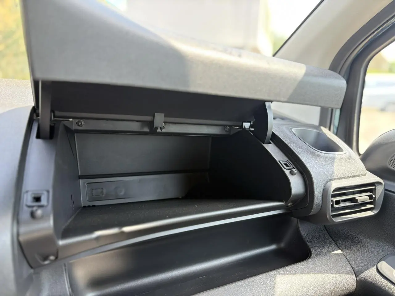 Vue rapprochée de la boîte à gants ouverte côté passager du Citroën Berlingo ë-136 54kWh bleu Kiama.