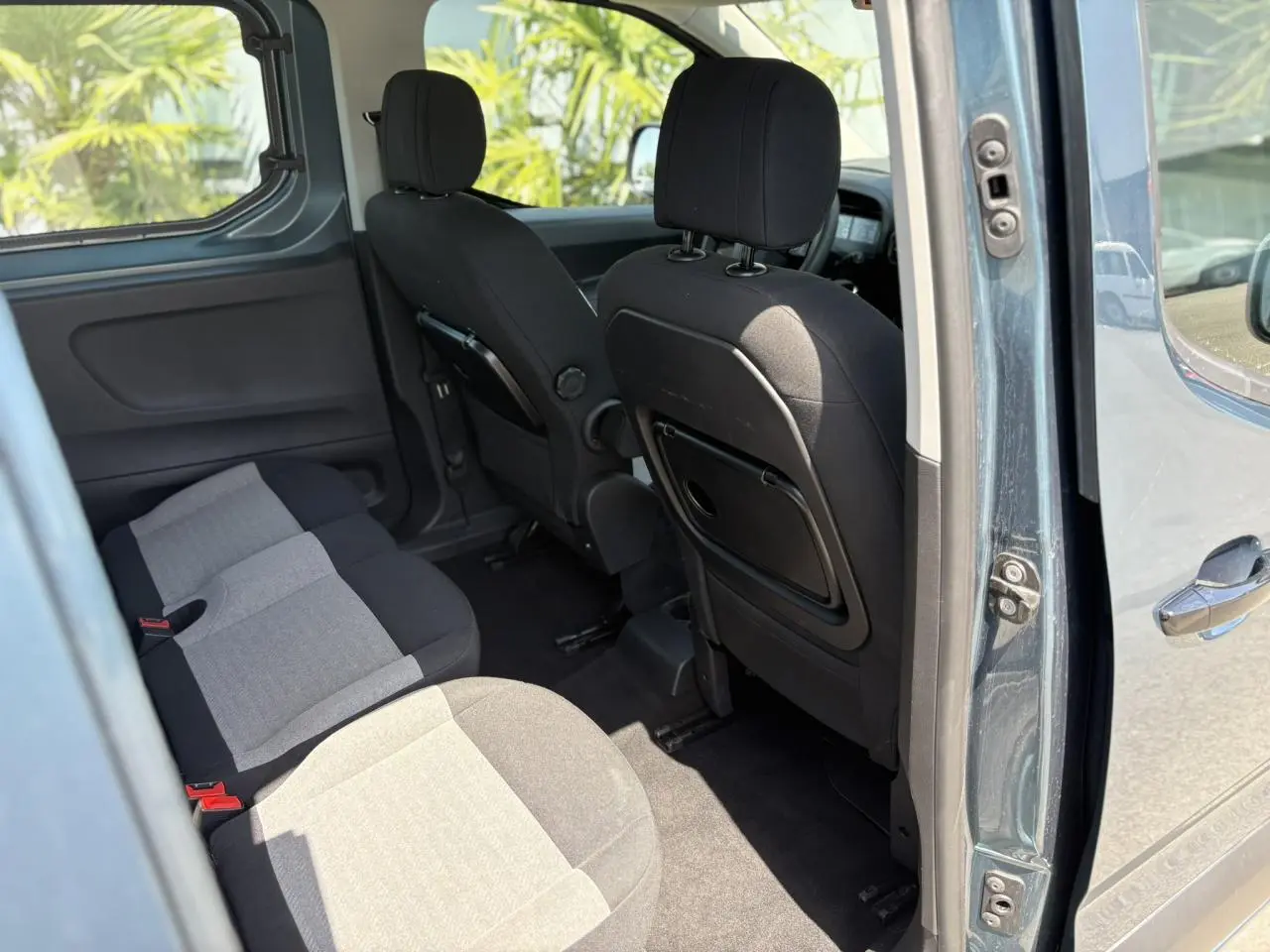 Vue intérieure côté droit du Citroën Berlingo bleu Kiama 2025, montrant la banquette arrière et les sièges avant avec tablettes rabattables.