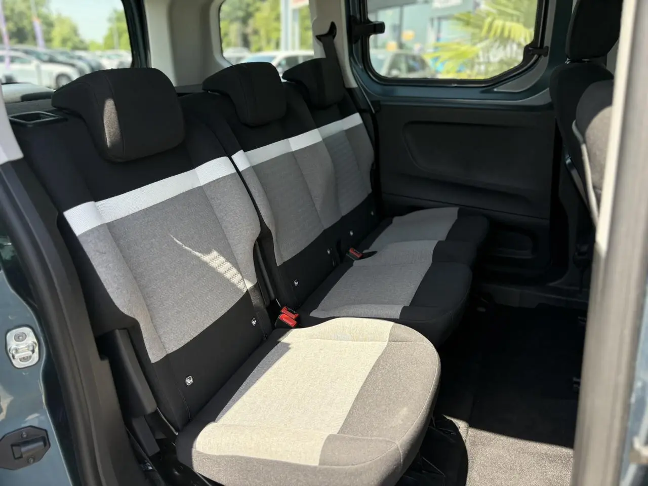 Vue intérieure sur la banquette arrière grise et noire du Citroën Berlingo ë-136 2025, avec porte coulissante ouverte.