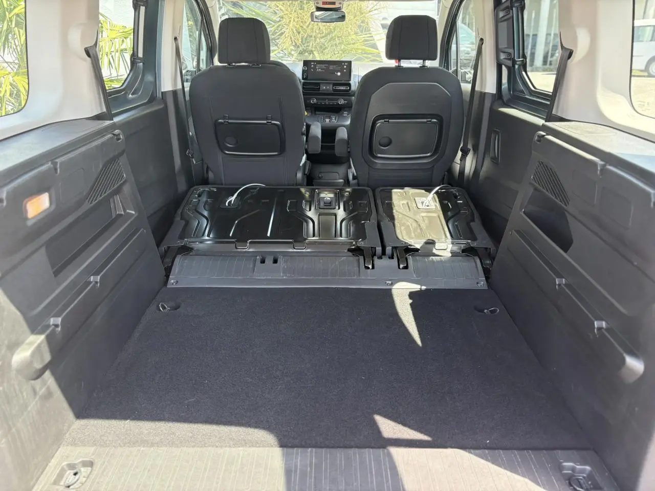 Vue intérieure arrière du Citroën Berlingo ë-136 2025, montrant la banquette rabattue et l'espace de chargement noir.