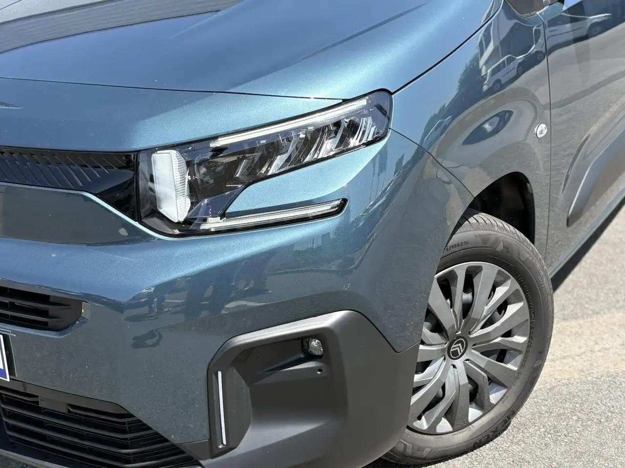 Gros plan sur l'avant droit bleu Kiama du Citroën Berlingo ë-136 avec phares LED et jante tôles 16 pouces.