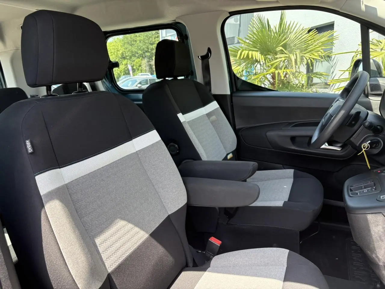 Vue intérieure côté droit du Citroën Berlingo ë-136 2025, sièges tissu noir et gris avec accoudoirs.