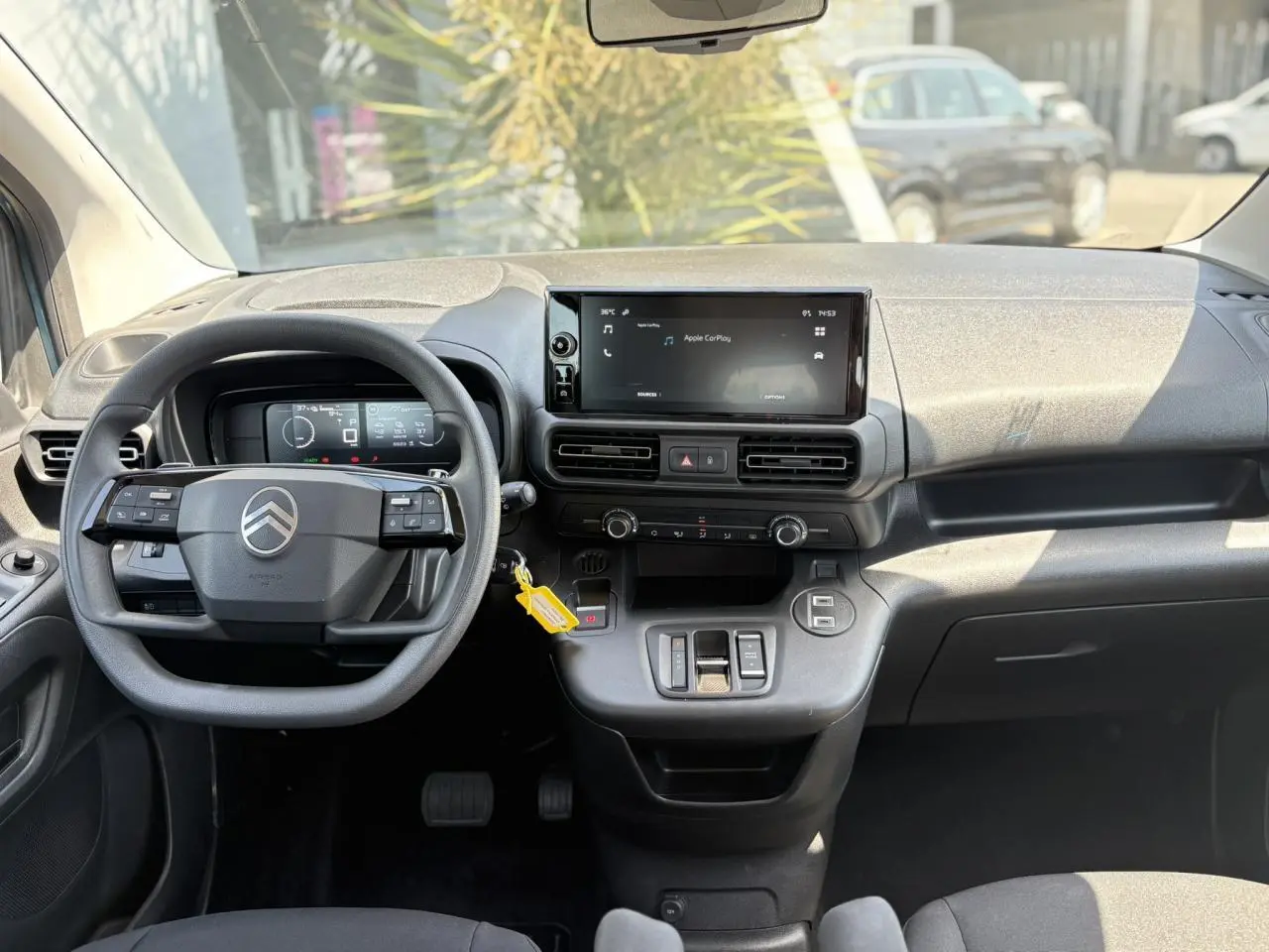 Vue intérieure avant du Citroën Berlingo ë-136 2025, tableau de bord avec écran tactile et volant multifonction noir.