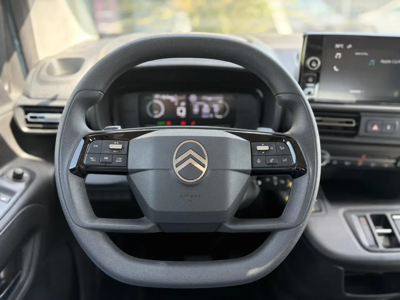 Vue centrée du volant multifonction noir du Citroën Berlingo ë-136 2025 avec tableau de bord numérique et écran tactile.