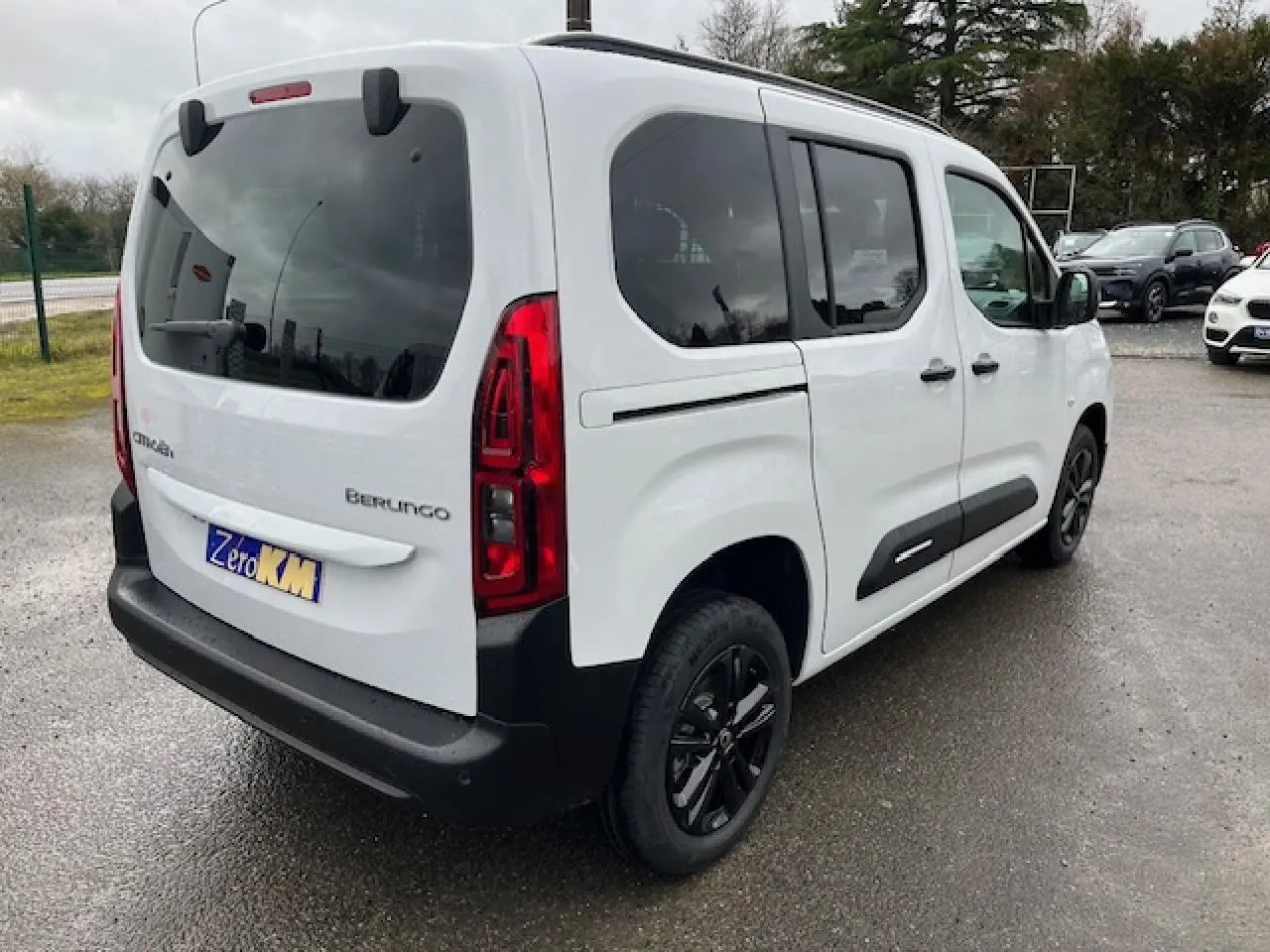 Vue 3/4 arrière droite du Citroën Berlingo Multispace blanc 2025 avec vitres teintées et protections noires sur les portes.