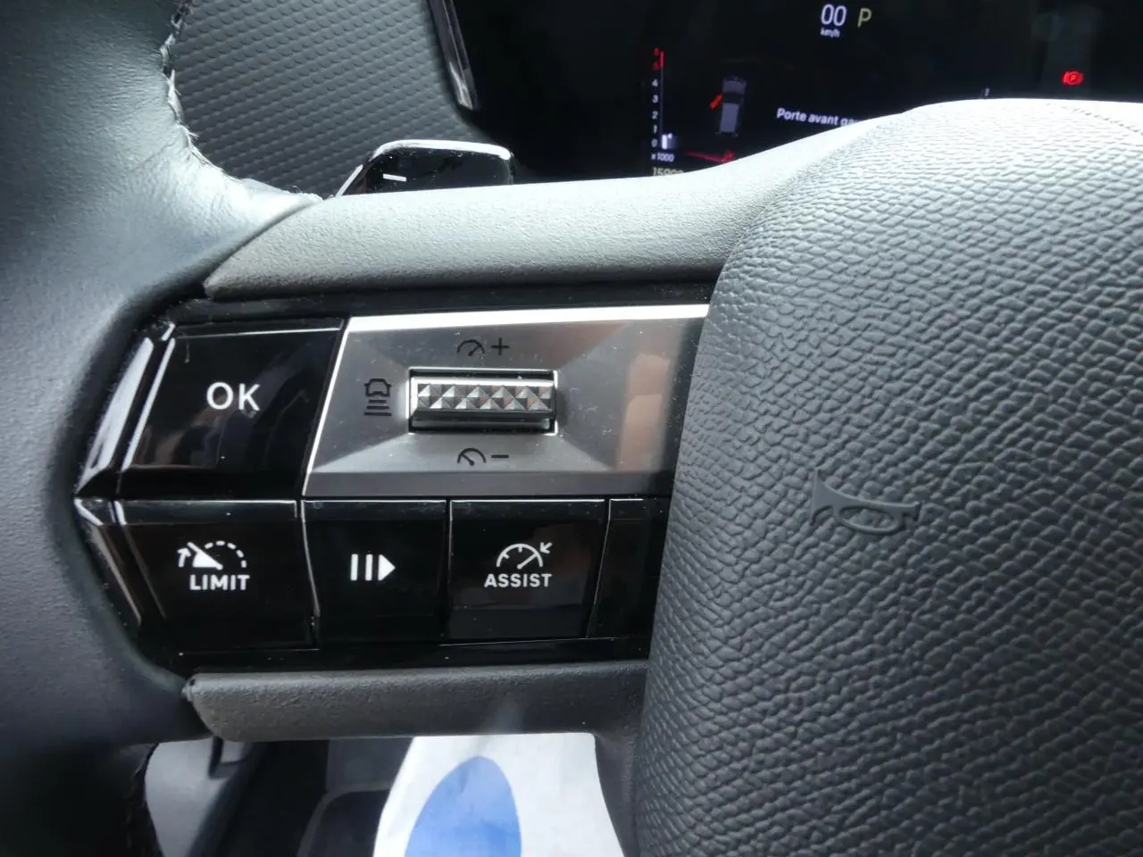 Gros plan sur les commandes de régulateur et assistant de conduite au volant cuir noir du DS4 gris métallisé 2024.