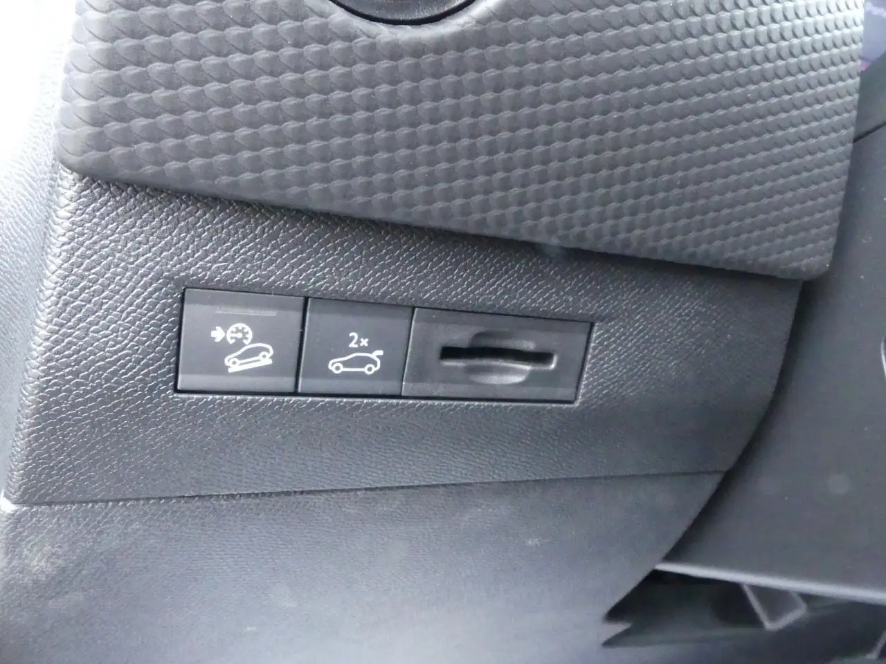 Gros plan sur les commandes de régulateur de vitesse et ouverture du coffre dans l'habitacle du DS4 gris métallisé 2024.