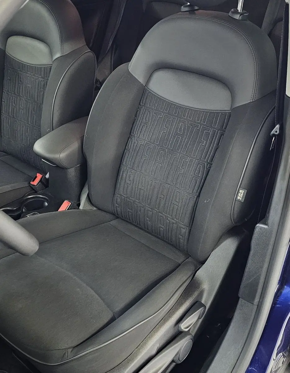 Vue intérieure côté conducteur du siège avant noir avec motifs FIAT, dans une FIAT 500X bleu 2024.