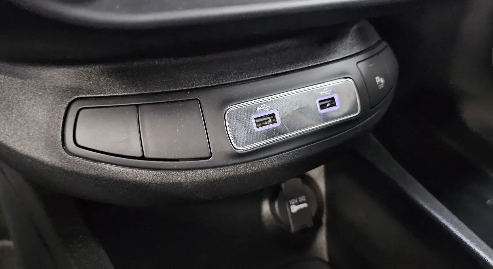 Gros plan sur les ports USB doubles et prise 12V dans l'habitacle noir du FIAT 500X Ph2 hybride 2024.