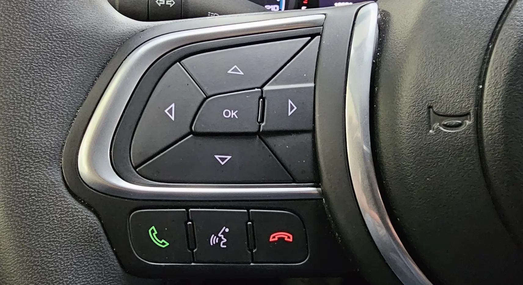 Gros plan sur les commandes multifonctions du volant noir du FIAT 500X hybride 2024, avec boutons d'appel et navigation.