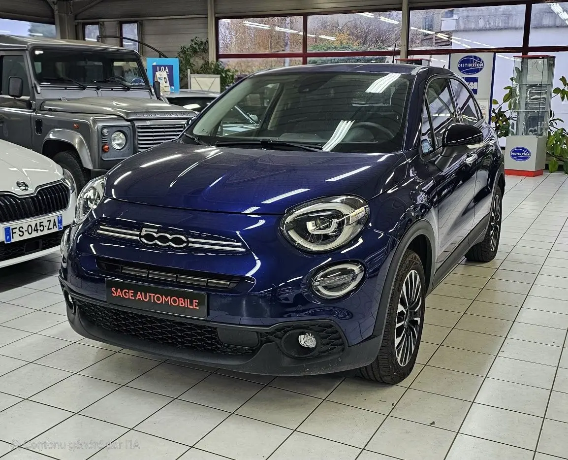 Vue 3/4 avant droite d'une FIAT 500X bleu 2024 avec logo 500 distinctif et jantes alliage en showroom.