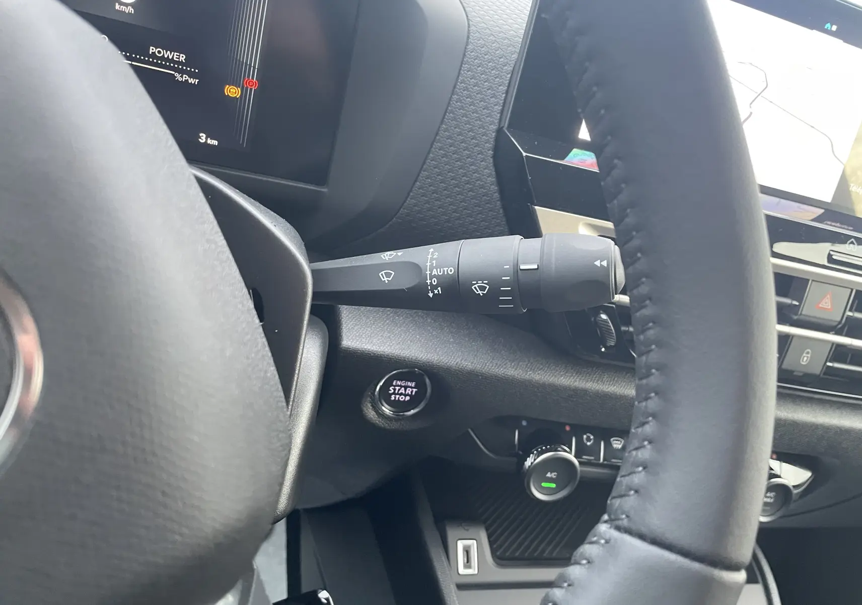 Vue rapprochée de l’intérieur du Citroën C4 hybride 2025, montrant le volant, le bouton start/stop et les commandes du tableau de bord.