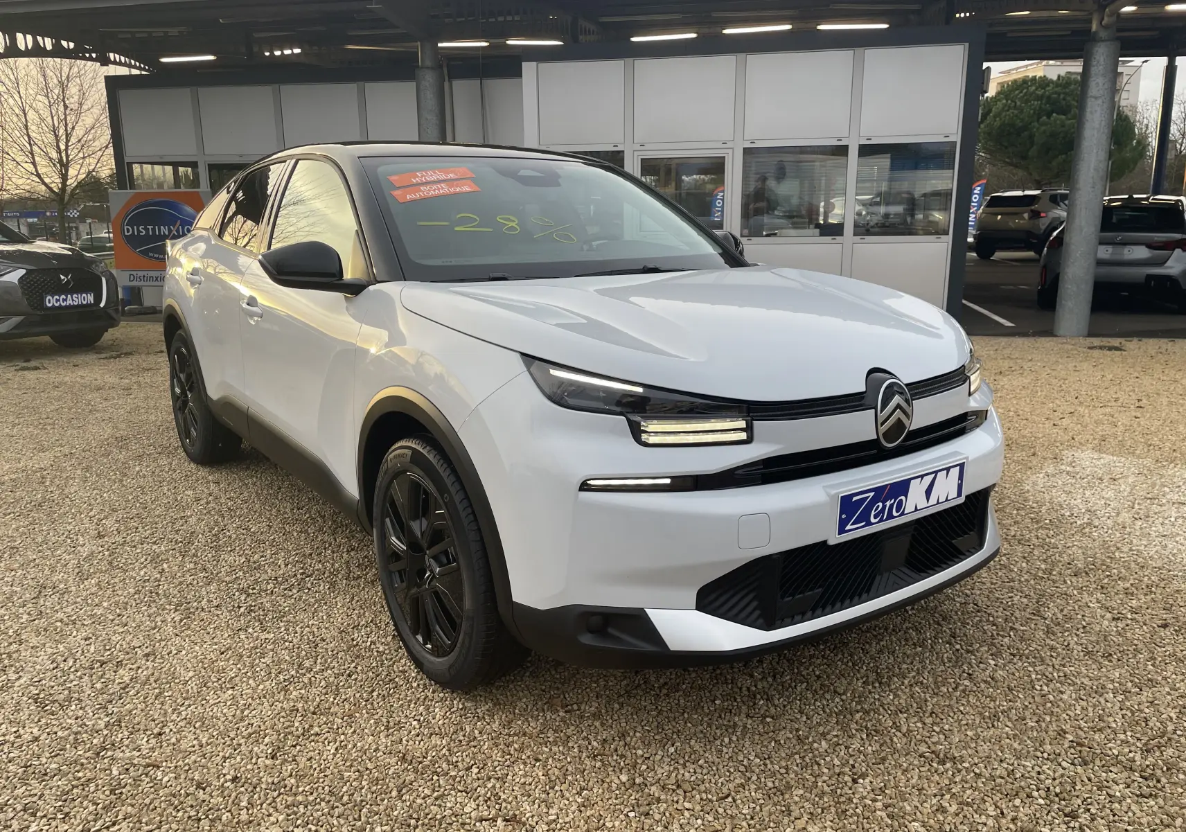 Citroën C4 hybride blanche avec toit noir, vue 3/4 avant droit, jantes noires et calandre distinctive.