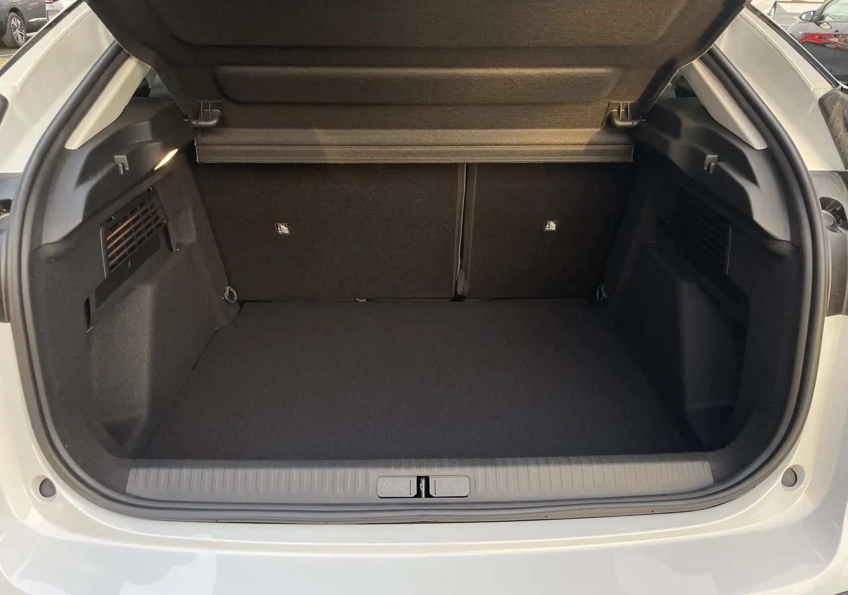 Coffre ouvert vu de l'arrière d'une Citroën C4 blanche Okenite avec toit noir, montrant un espace de chargement propre et vide.
