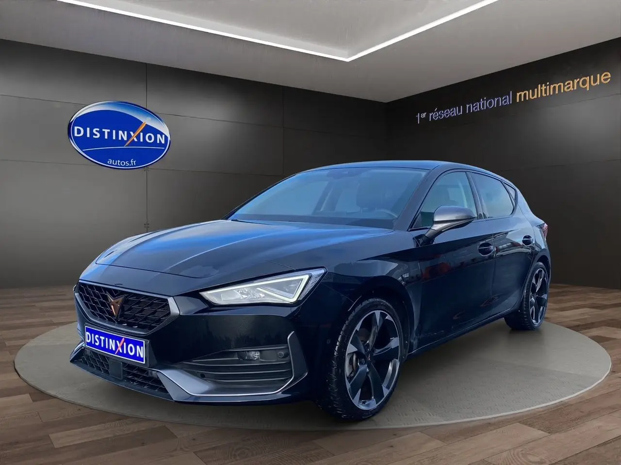 Vue 3/4 avant droite d'une CUPRA Leon noire 2023 avec jantes noires et calandre distinctive en showroom.