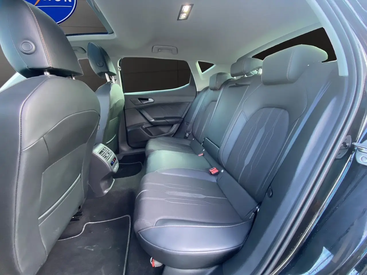 Vue intérieure côté droit des sièges arrière en cuir noir d'une CUPRA Leon 2023 avec toit ouvrant panoramique.