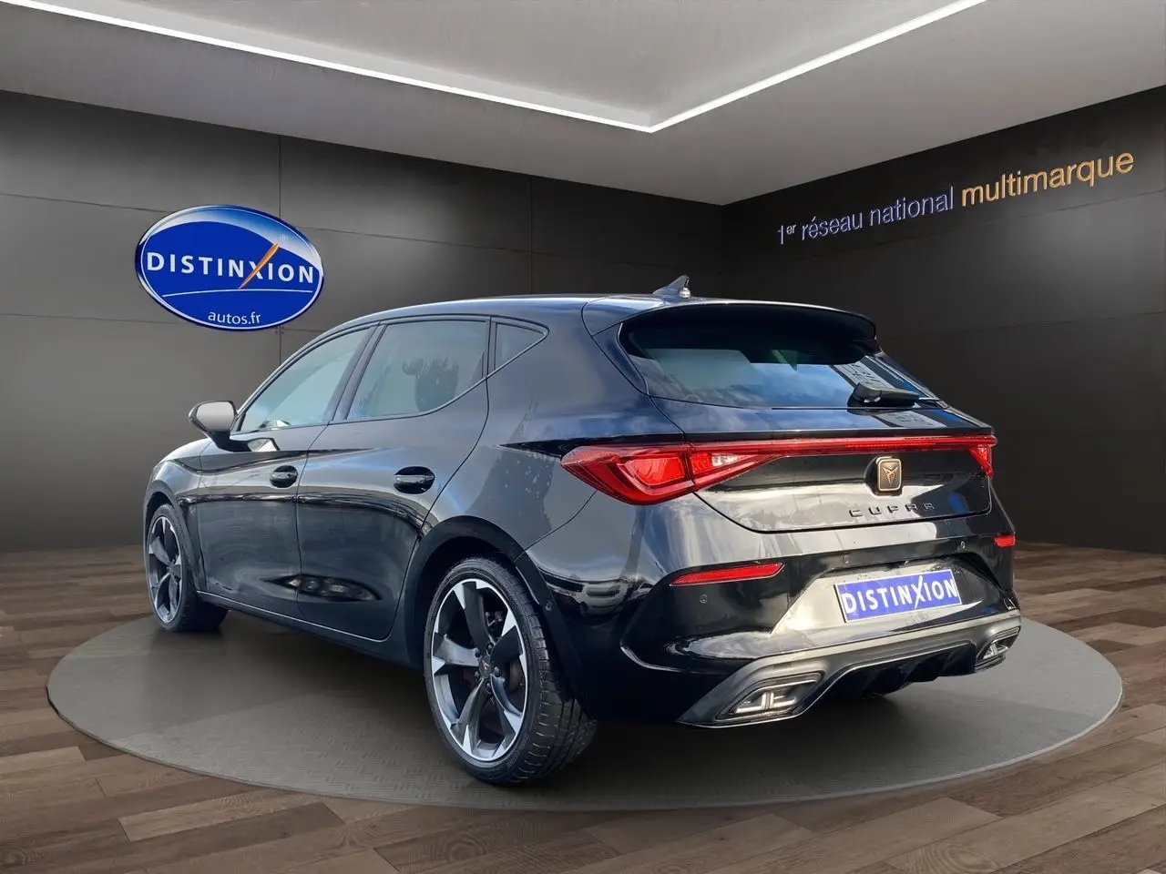 Vue 3/4 arrière droite d'une CUPRA Leon noire 2023 avec jantes bi-ton et feux arrière LED intégrés.